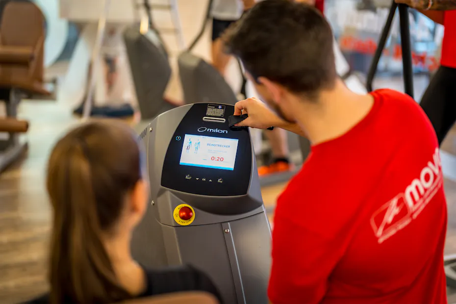 Mitglied trainiert an der milon Konsole, persönlich betreut von einem Trainer