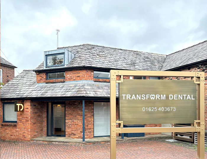 Brick building with slate roof and a sign reading "Transform Dental" with a contact phone number in front.