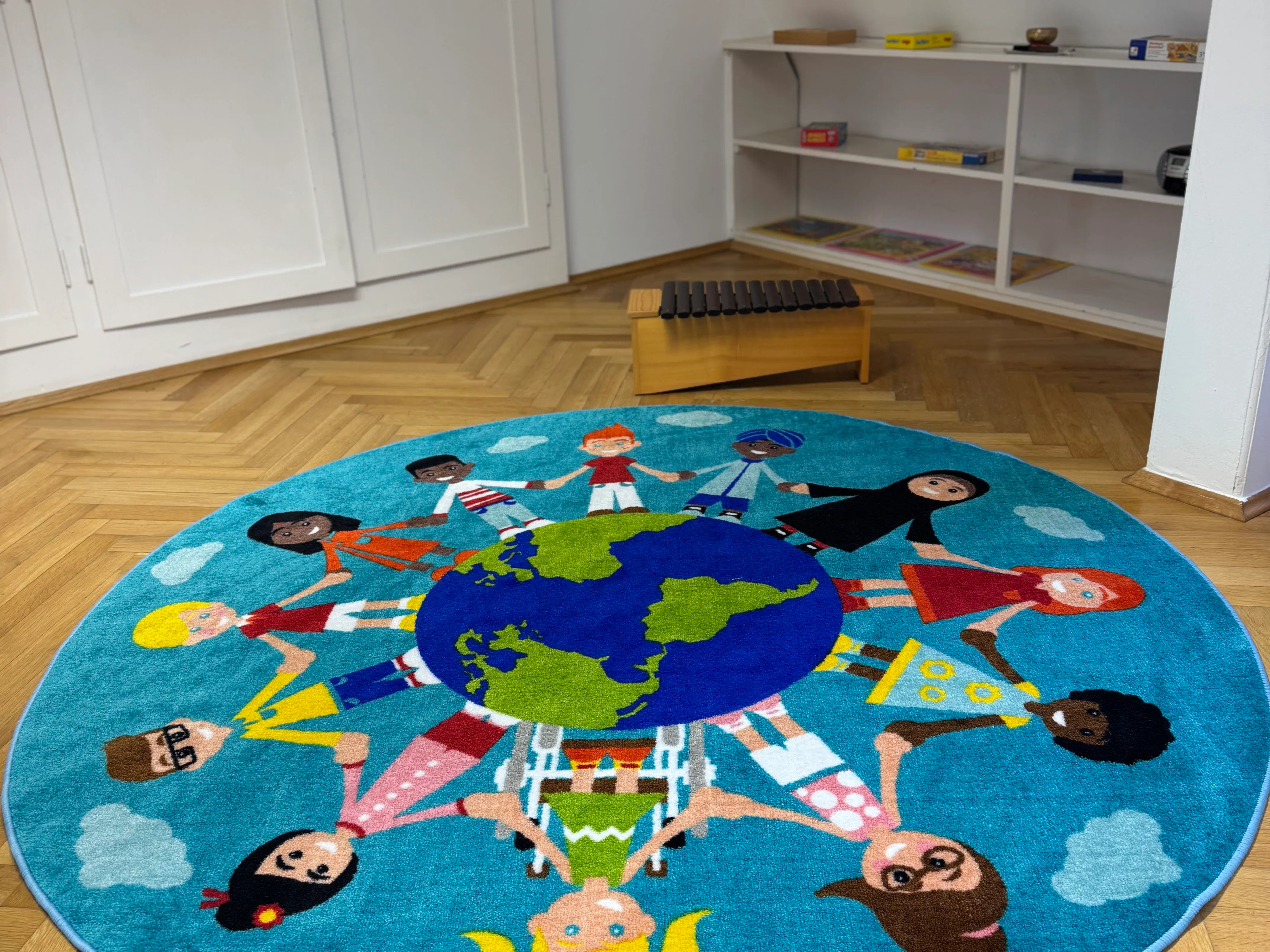Bunter runder Teppich mit Kindern unterschiedlicher Ethnien und Kleidung, die die Erde in der Mitte umarmen, in einem Raum mit Holzfußboden und einem Holzinstrument im Hintergrund.