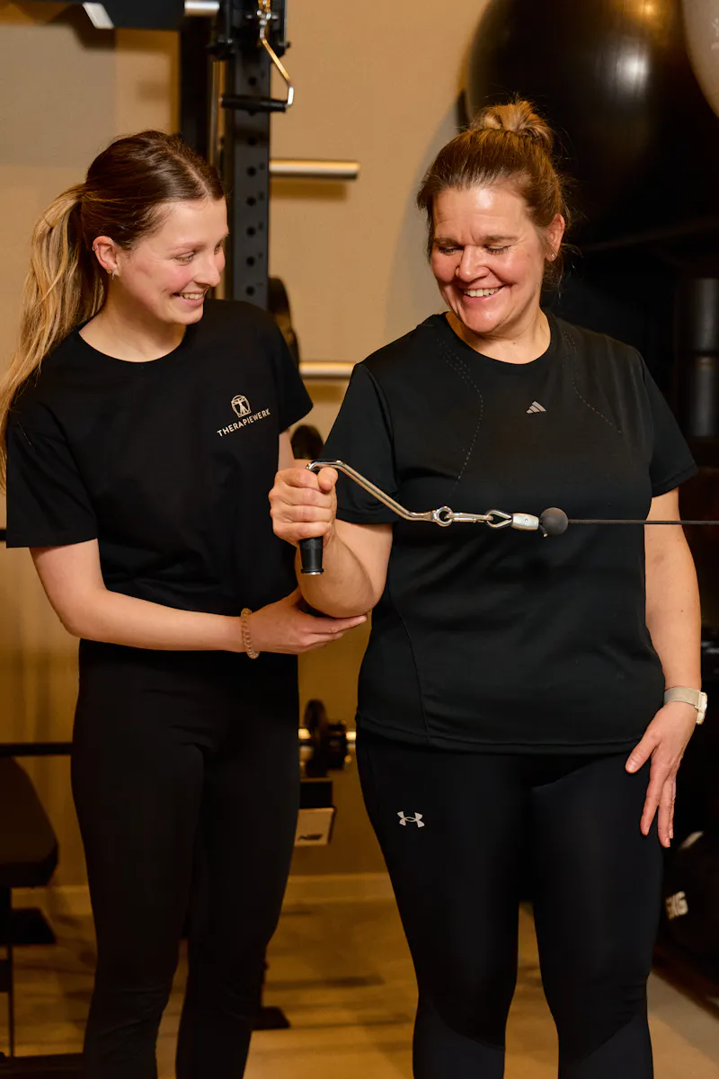 Physiotherapeutin begleitet eine Patientin beim Training am Kabelzug