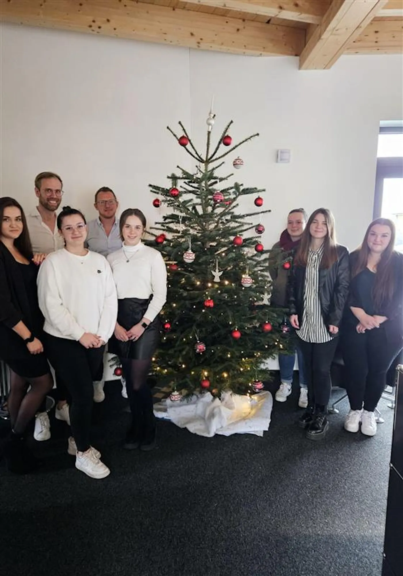 Team vor dem Weihnachtsbaum im Büro