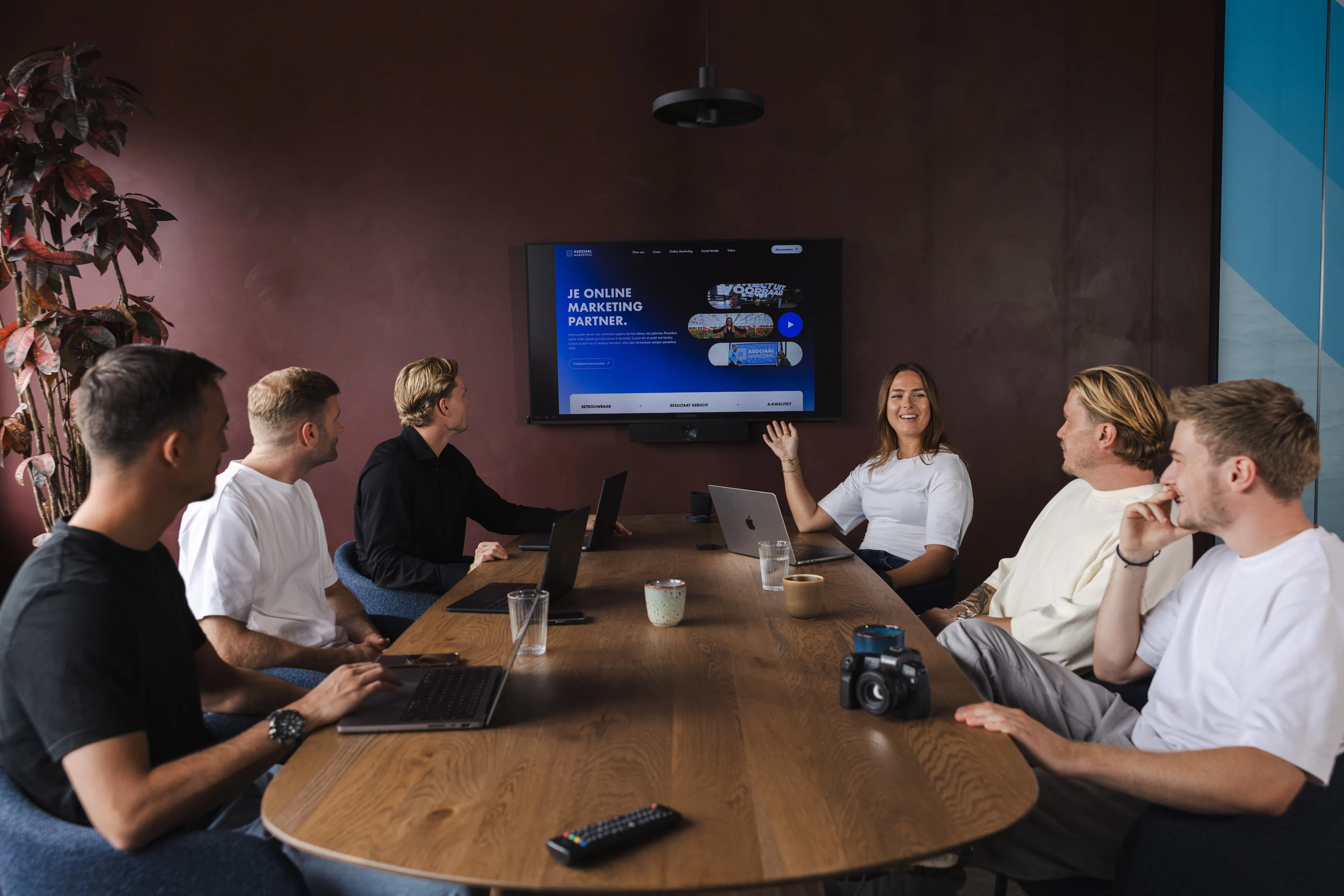 Asociaal Marketing team in een vergadering met laptops en presentatiescherm