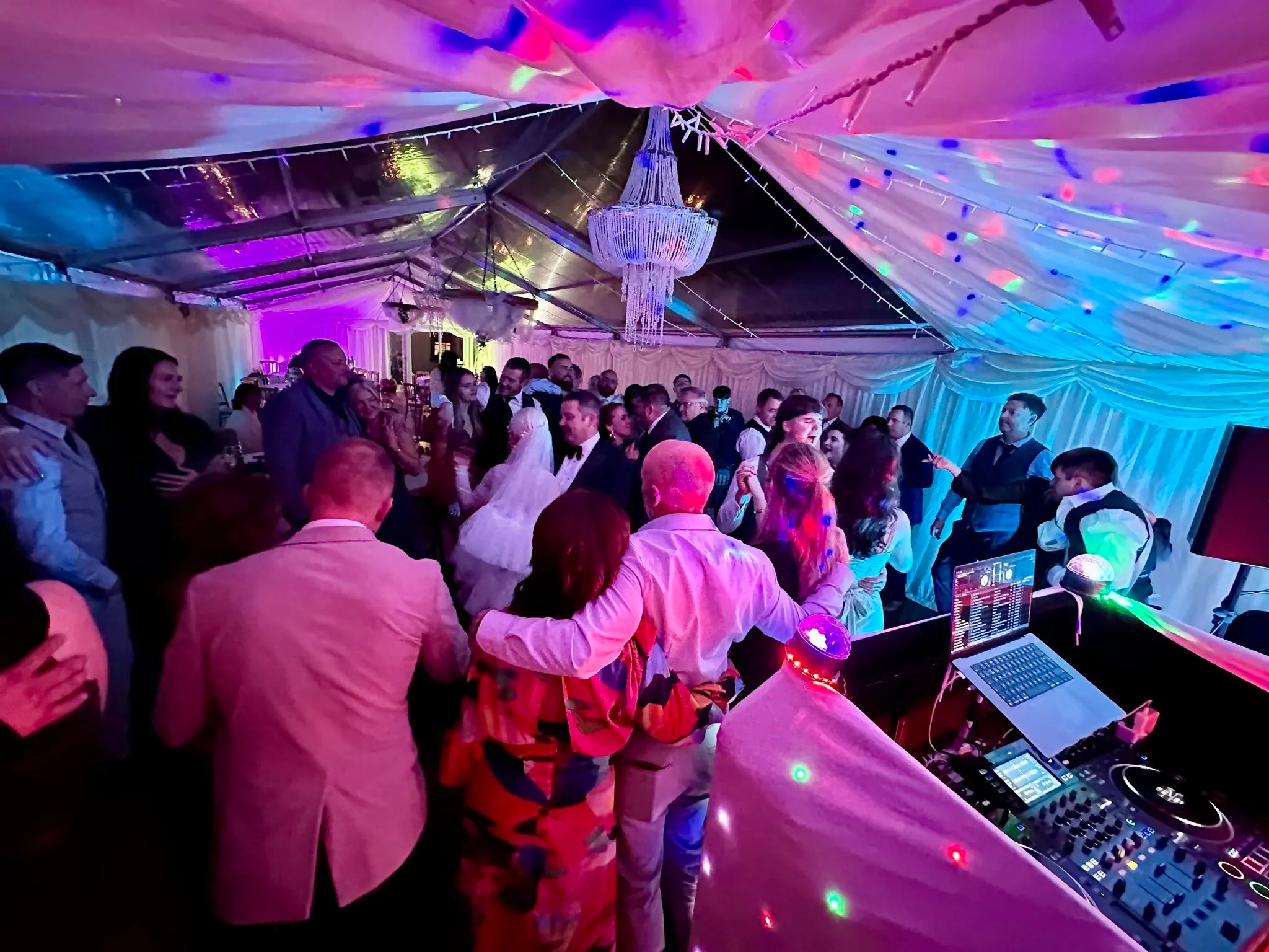 packed wedding dancefloor with colourful lights