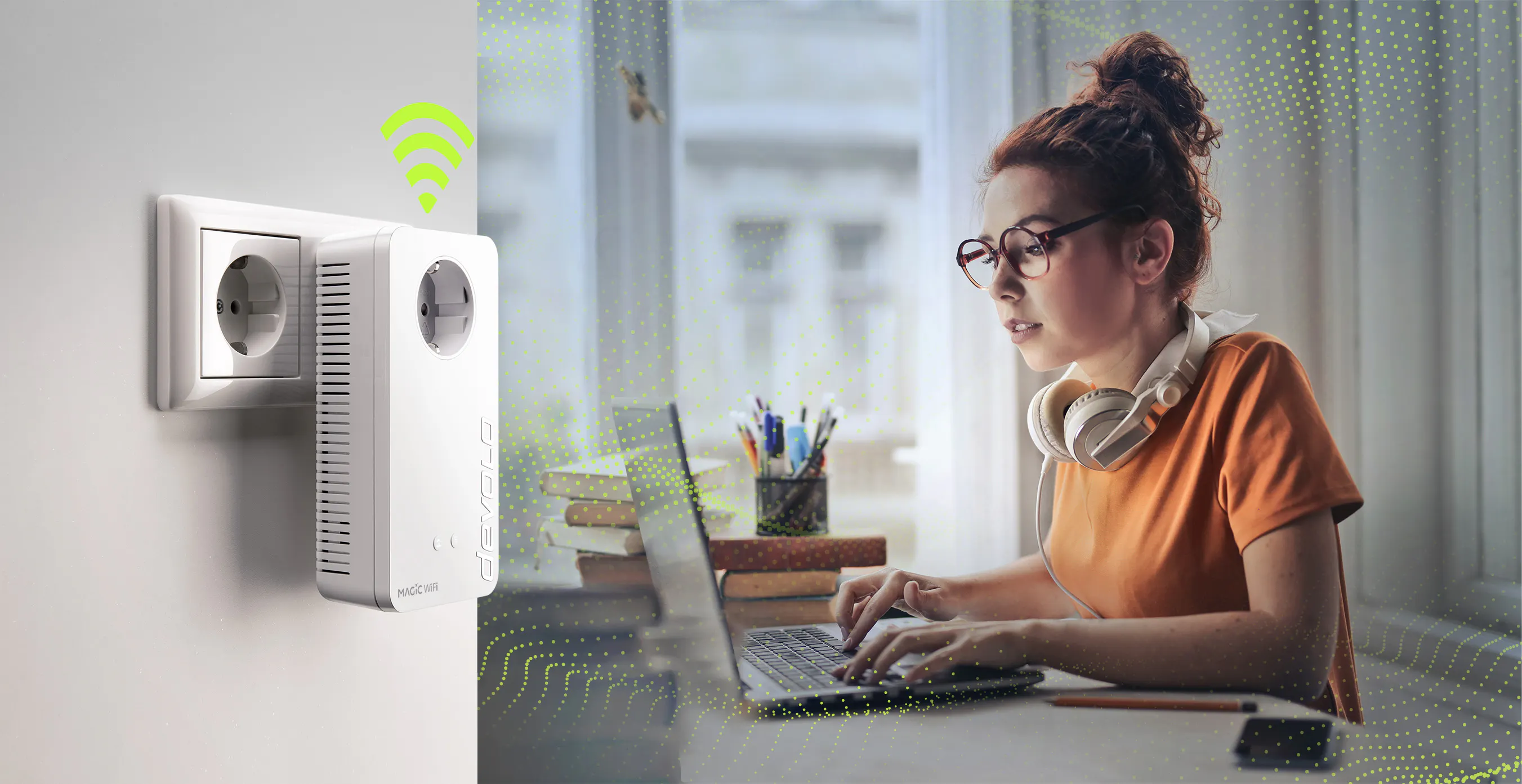 Frau mit Brille und Kopfhörern sitzt an einem Tisch und arbeitet am Laptop, daneben ist ein Devolo Magic WiFi Adapter in einer Steckdose mit WLAN-Symbol.
