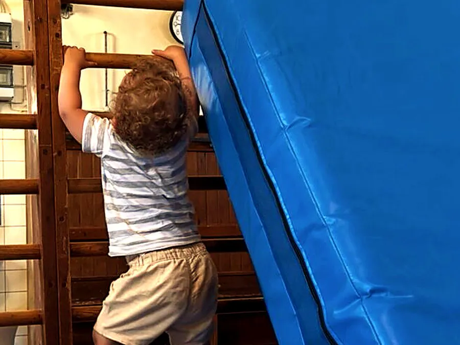 Minis: Kleinkind klettert an der Sprossenwand