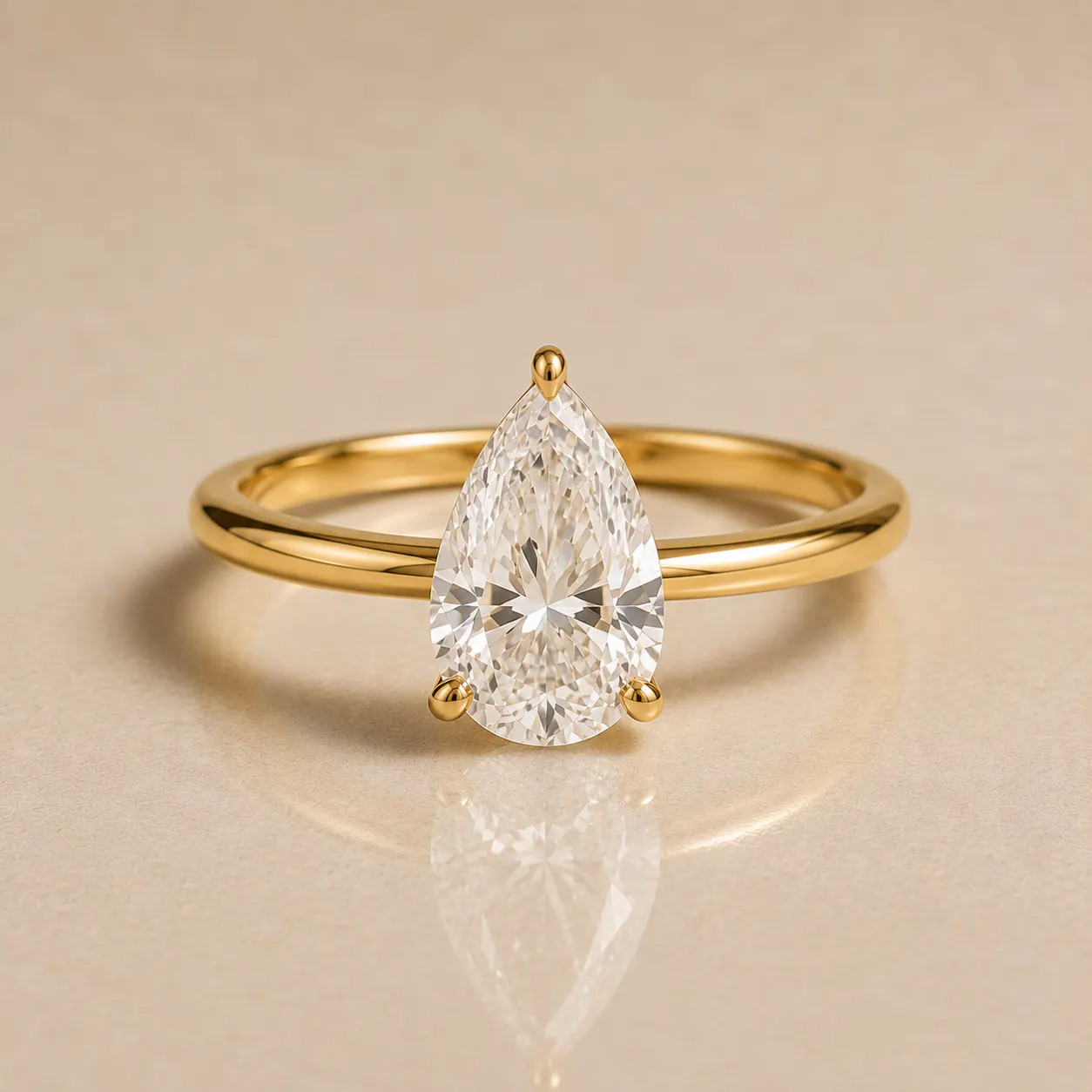 Gold ring with a large pear-shaped clear gemstone set in a three-prong setting displayed on a beige surface.