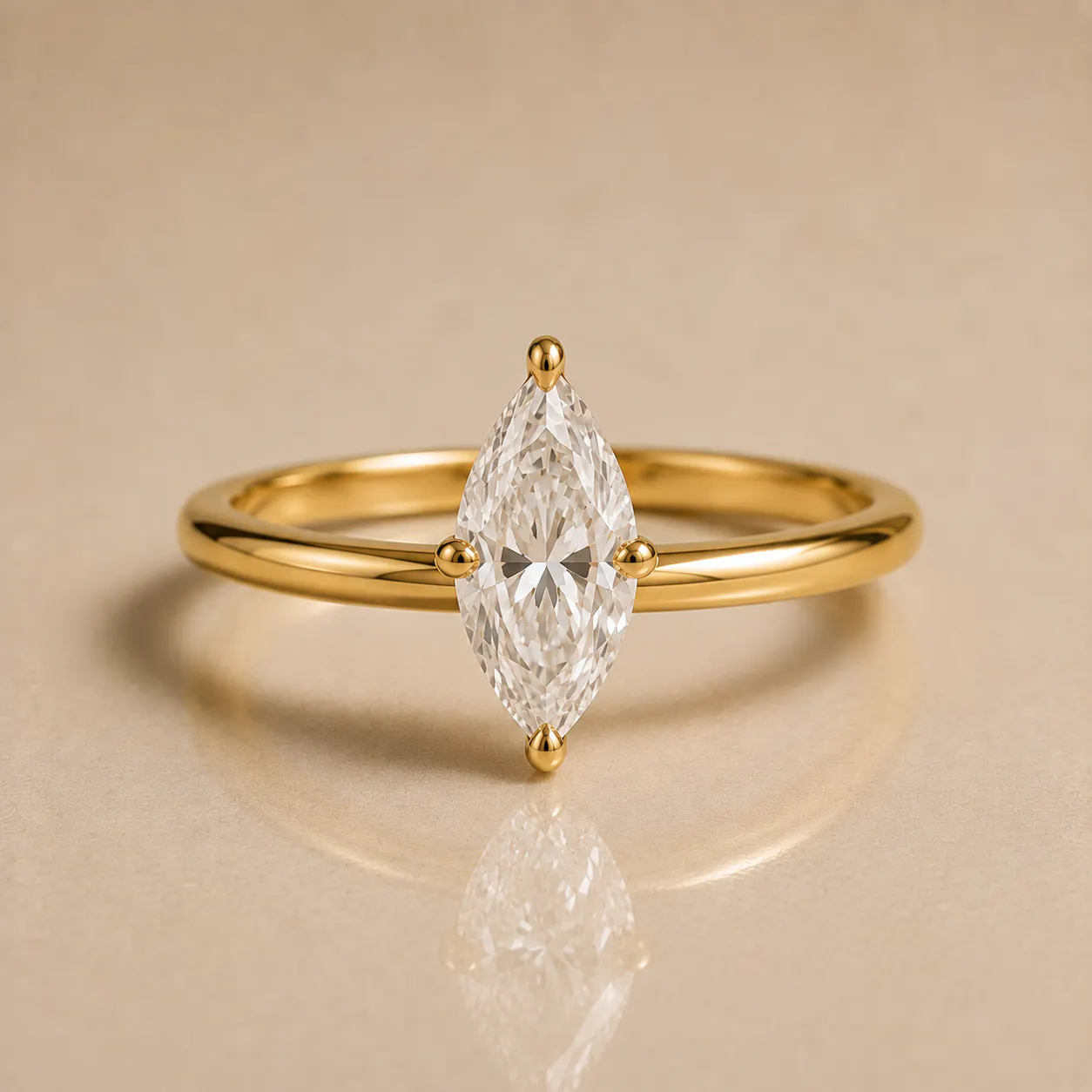 Gold ring with a marquise-cut diamond held by four prongs, placed on a smooth beige surface with the diamond's reflection visible below.