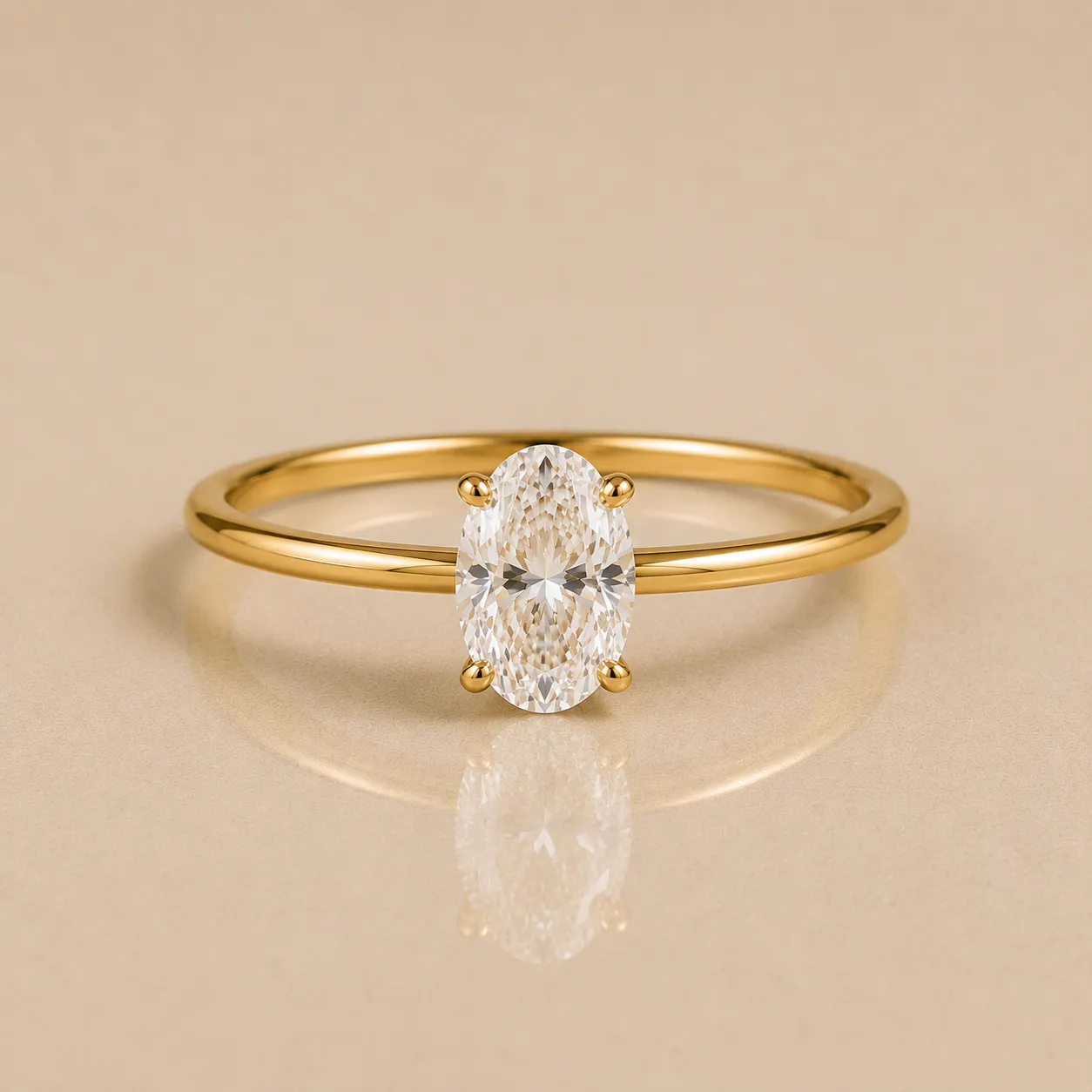 Gold band ring with an oval-shaped clear gemstone held by four prongs, reflected on a smooth beige surface.