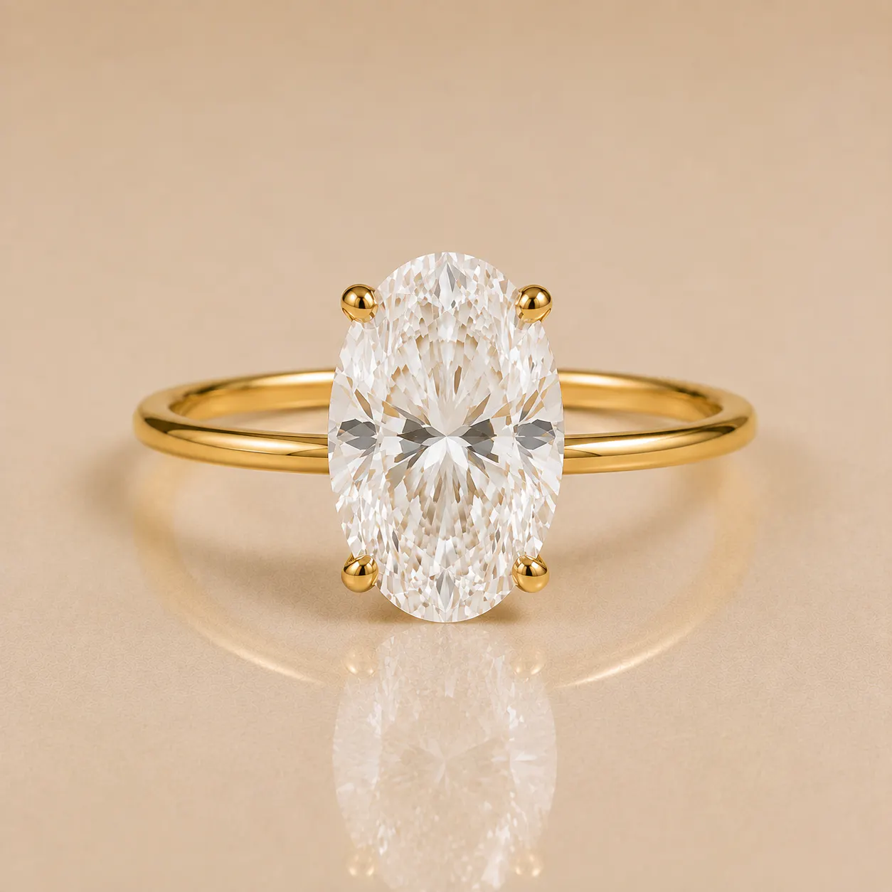 Oval-shaped clear gemstone set in a simple yellow gold band with four prongs on a beige reflective surface.