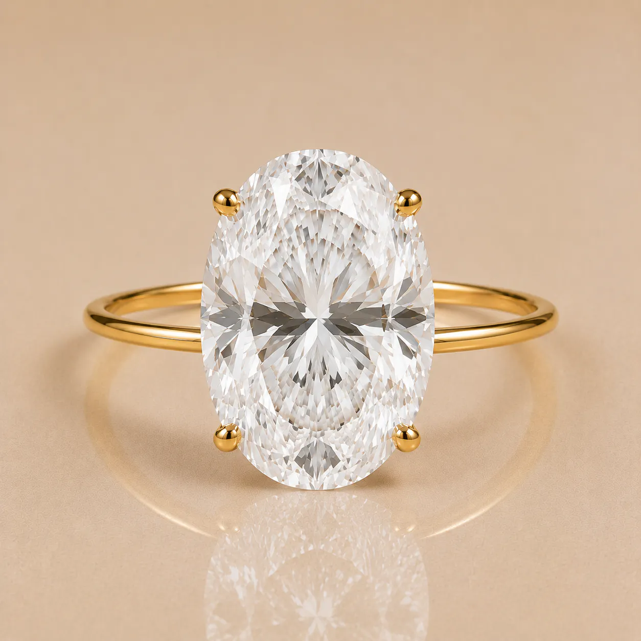 Oval-cut diamond solitaire set in a thin gold band with four prongs holding the diamond, reflecting light on a neutral beige surface.