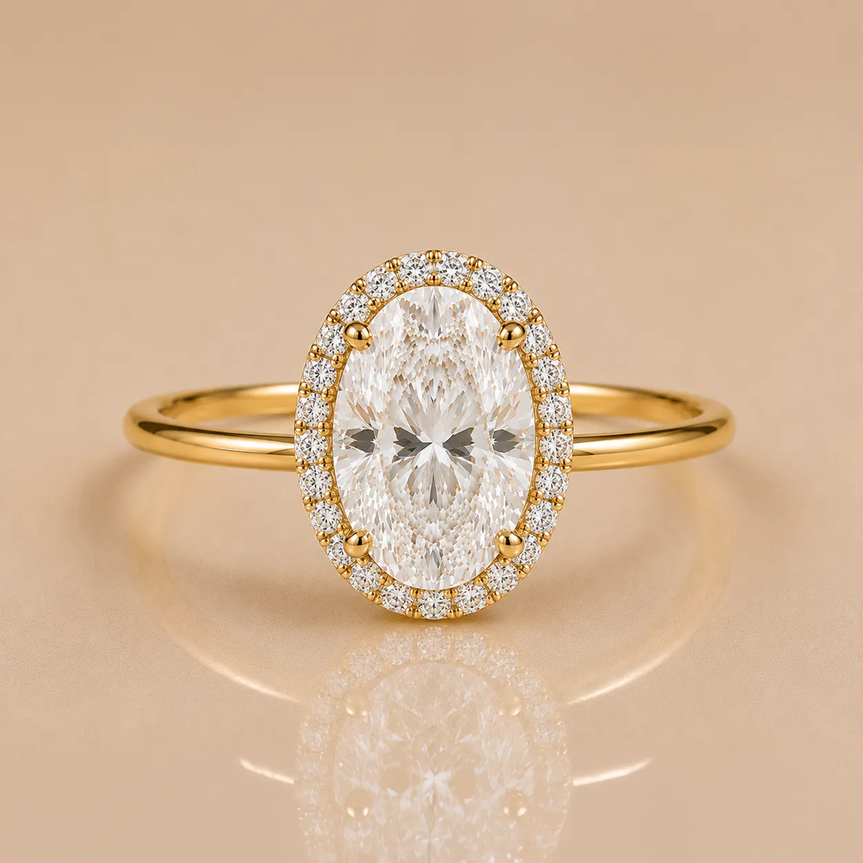 Gold ring with a large oval-cut central diamond surrounded by smaller round diamonds in a halo setting, reflecting on a beige surface.