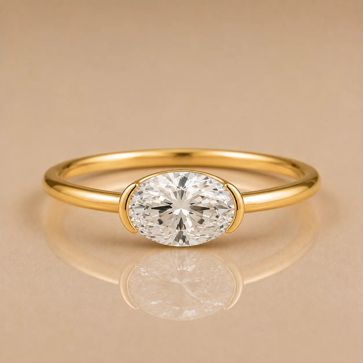 Gold ring with a polished band and an oval-cut clear diamond held by two prongs, reflected on a beige surface.