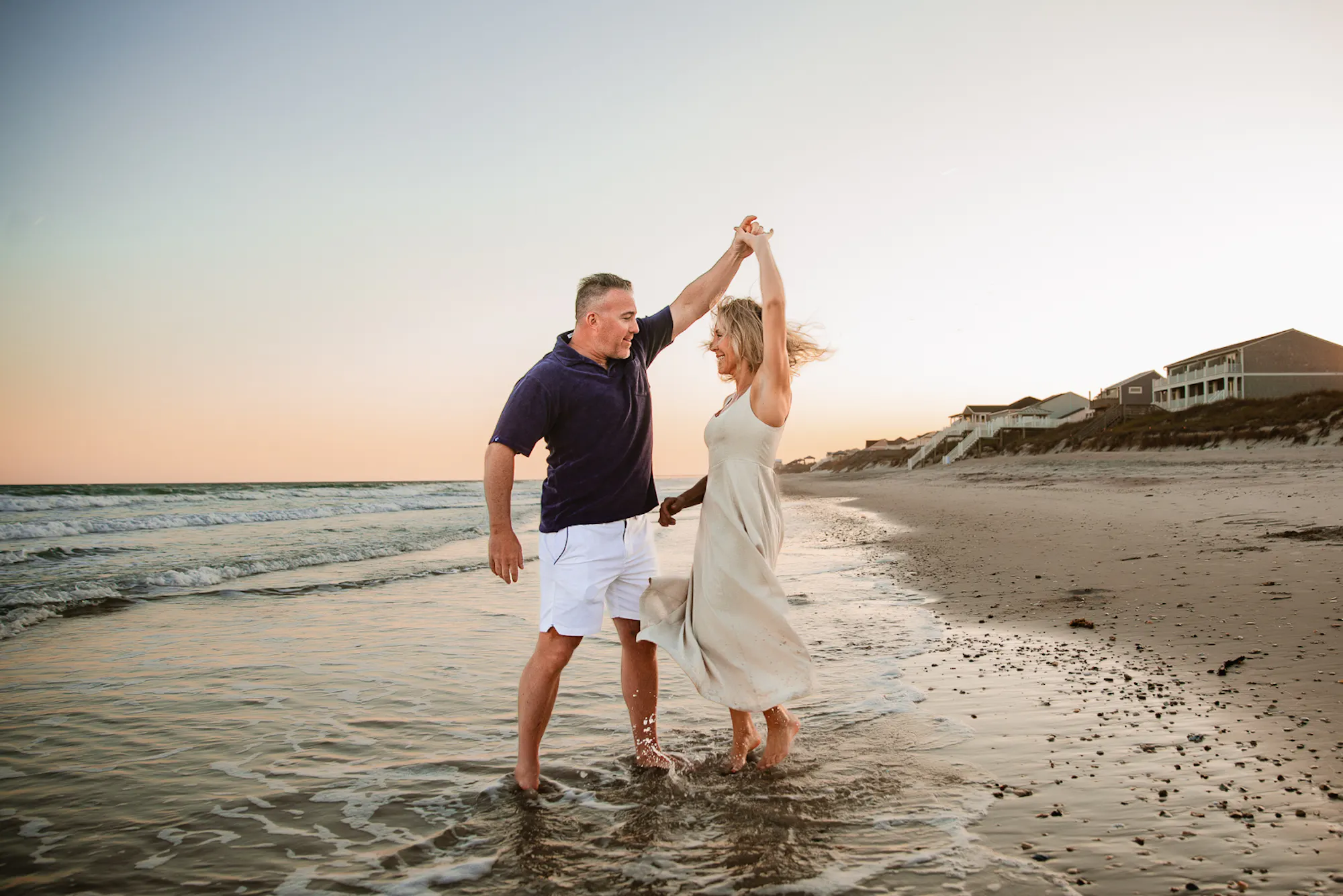 Couple dancing at the water's edge at sunset
