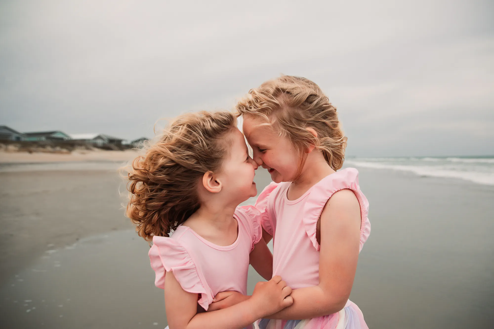 Two young sisters touching foreheads and laughing