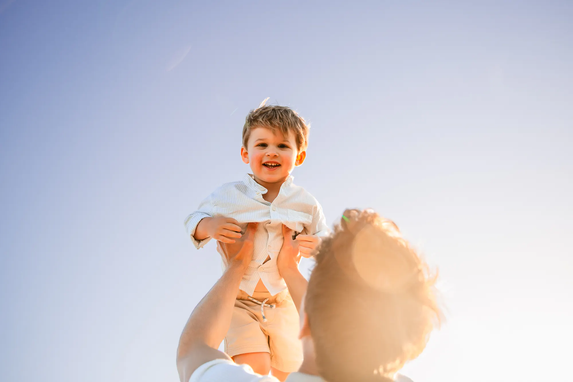 Father lifting his laughing son toward the sky