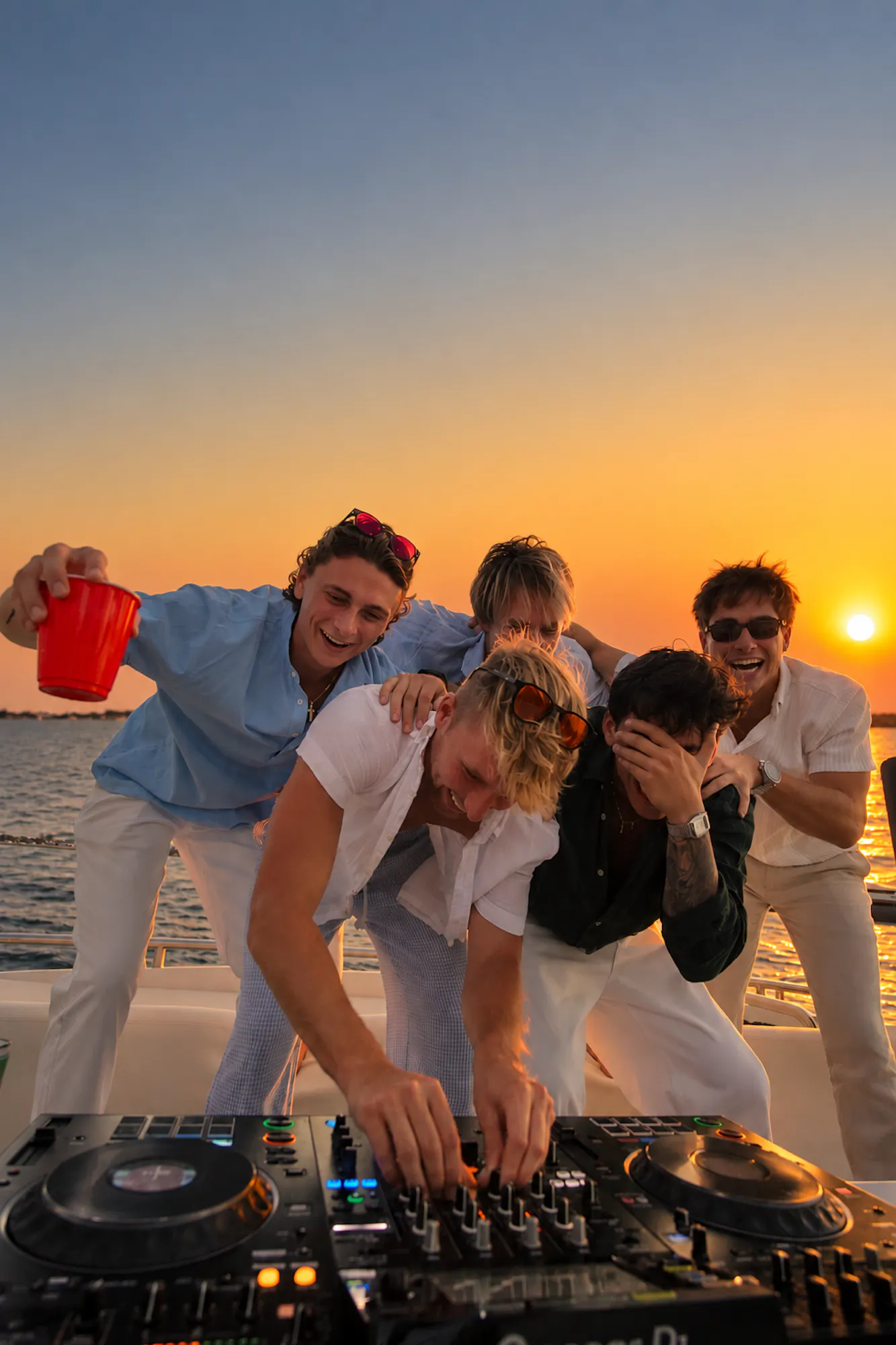 friends DJing on yacht at sunset