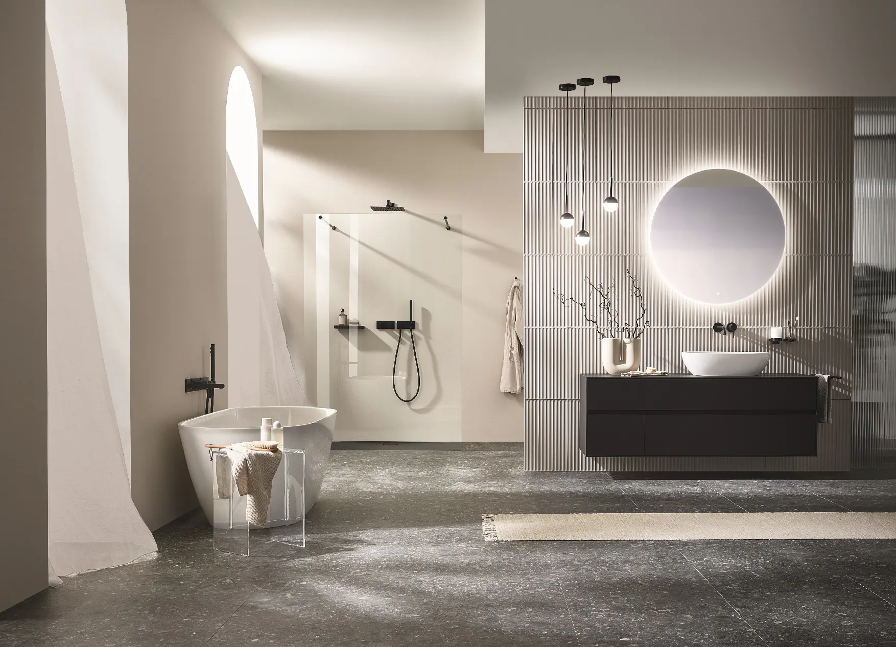 Modernes Badezimmer mit freistehender Badewanne, begehbarer Dusche, wandhängendem Waschbeckenunterschrank, rundem beleuchtetem Spiegel und minimalistischer Dekoration.