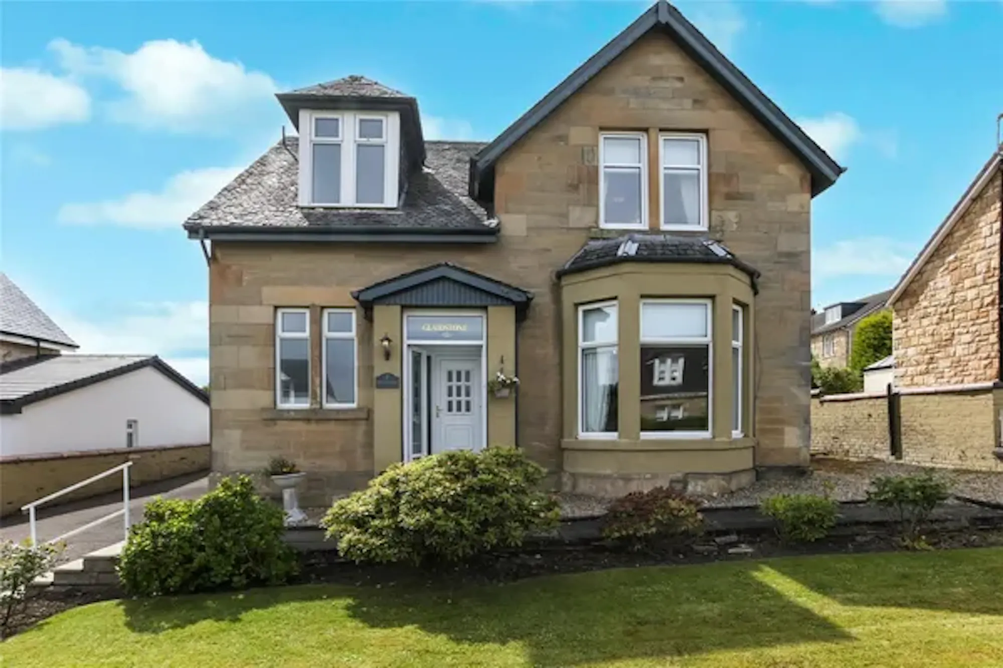 Sandstone detached house with bay window and front garden