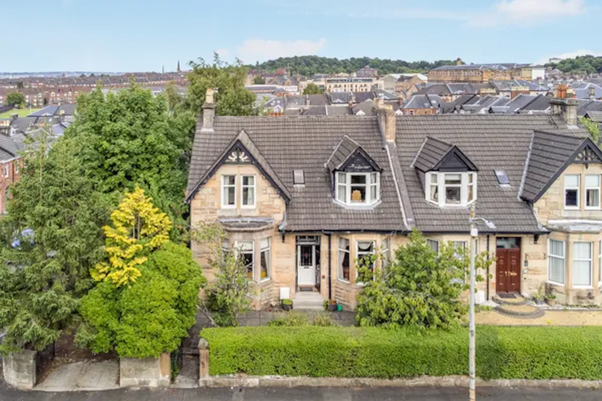 Semi-detached sandstone villas on a leafy residential street