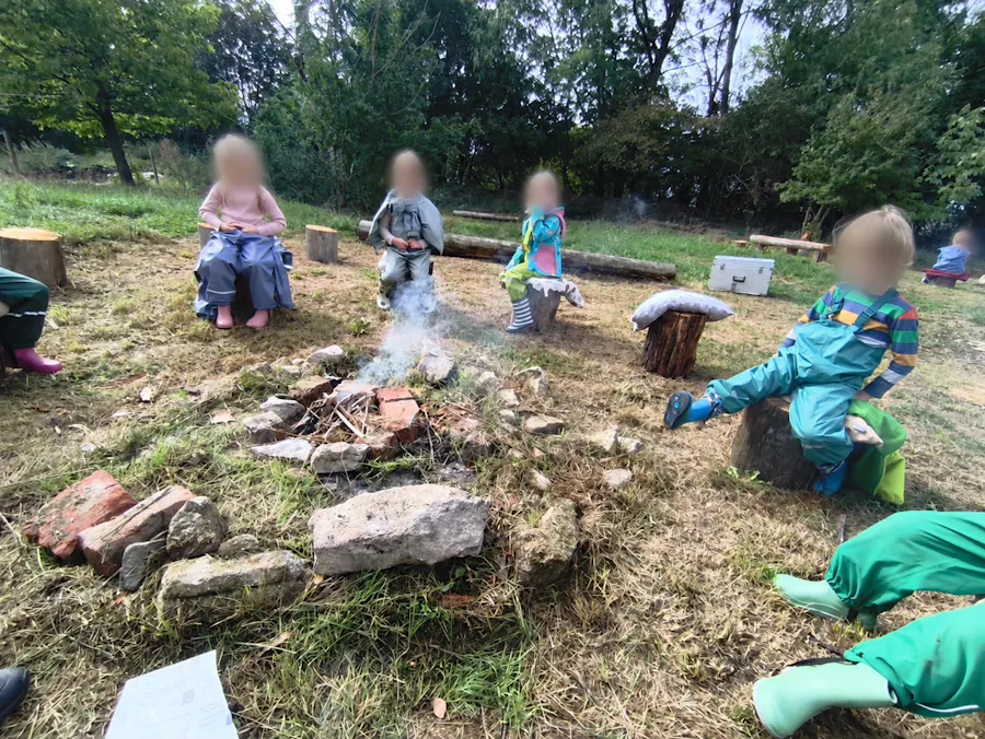 Kinder sitzen um die Feuerstelle
