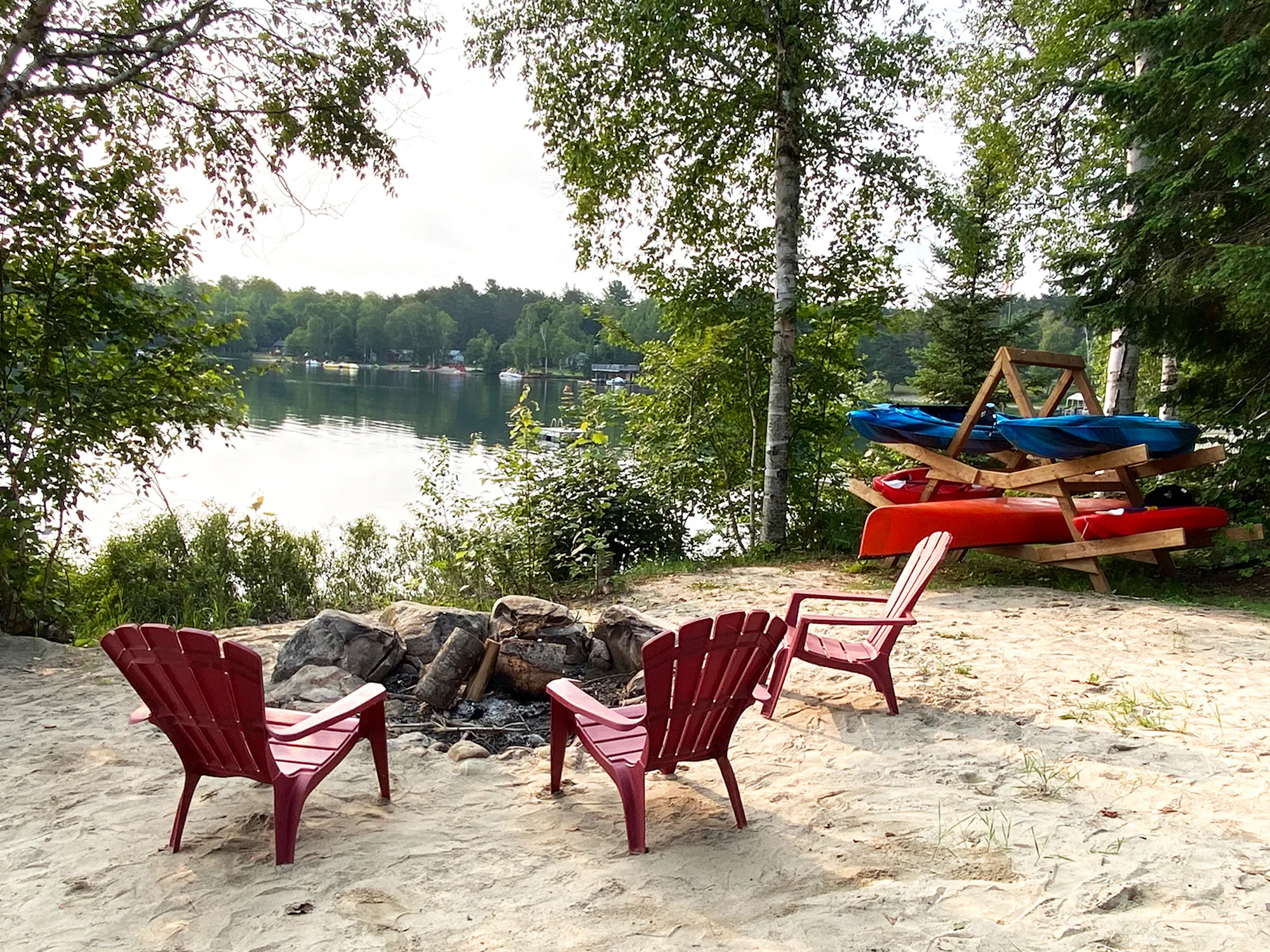 Lakeside fire pit with Muskoka chairs and kayaks at the Clear Lake cottage