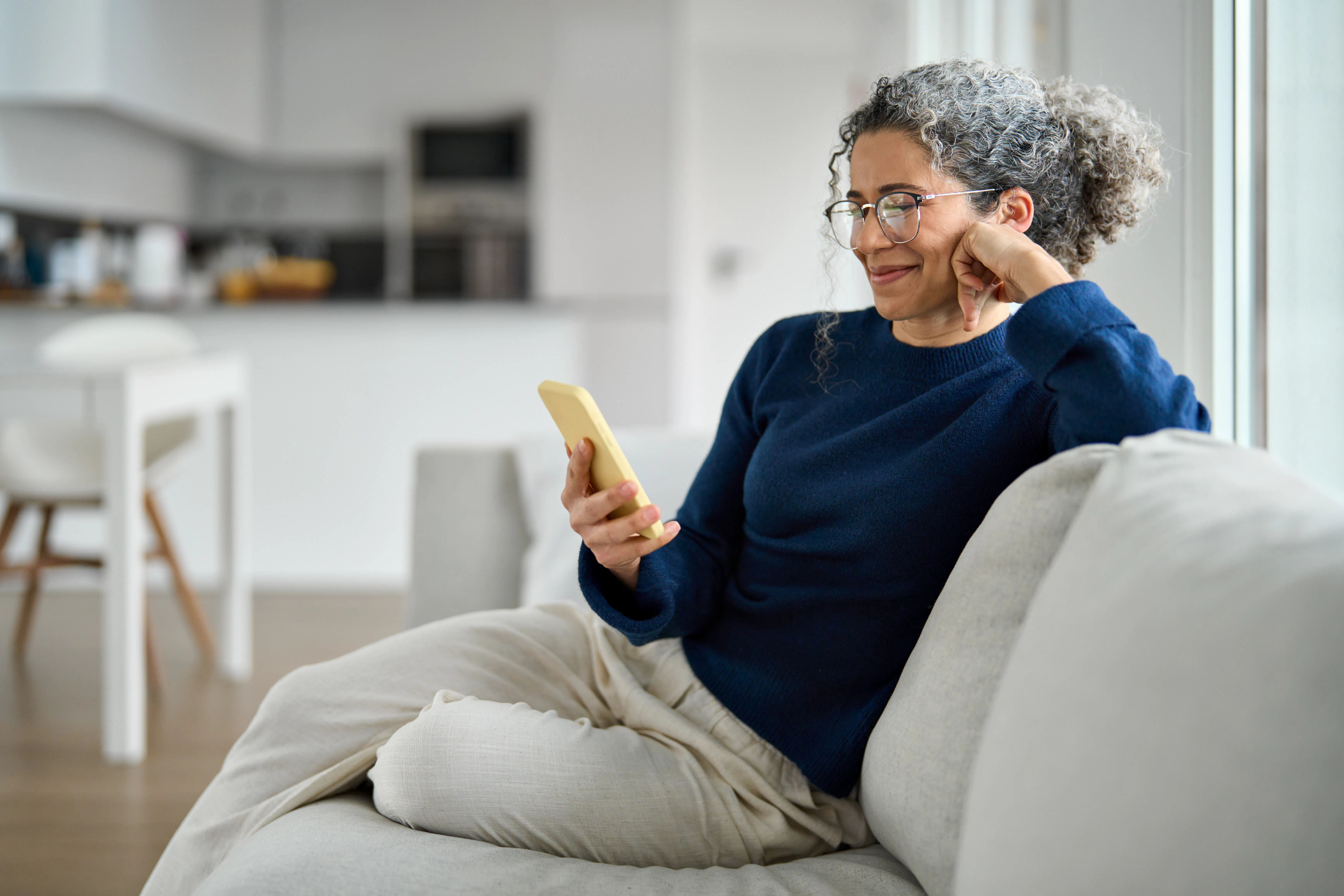 Smiling retiree relaxing on the couch with her phone