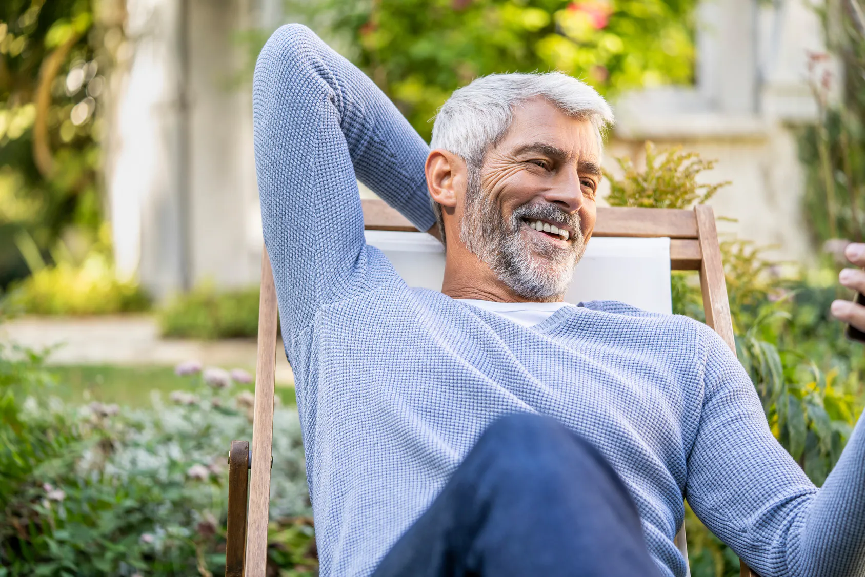Smiling retiree relaxing in a garden deck chair