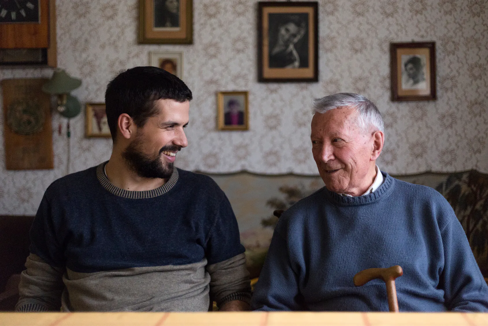 Grandfather smiling with his grown grandson at home