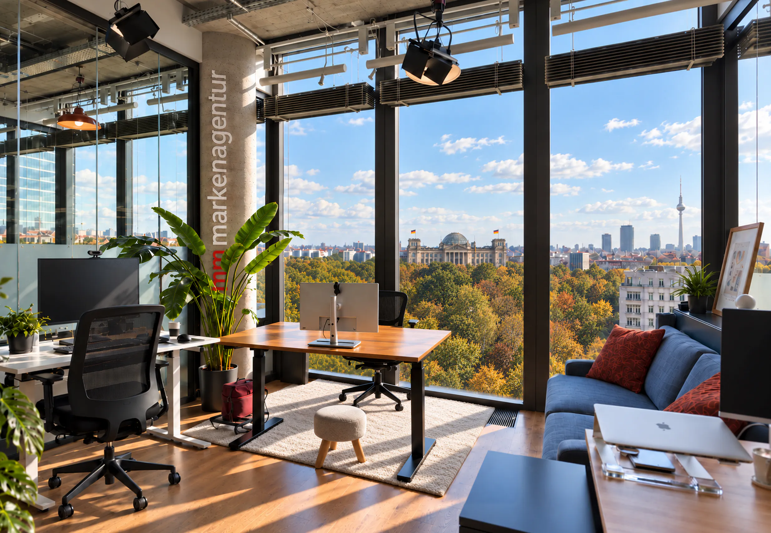 Helles Büro der mm markenagentur mit Schreibtischen, Pflanzen und Fensterfront mit Blick auf den Reichstag und den Berliner Fernsehturm.