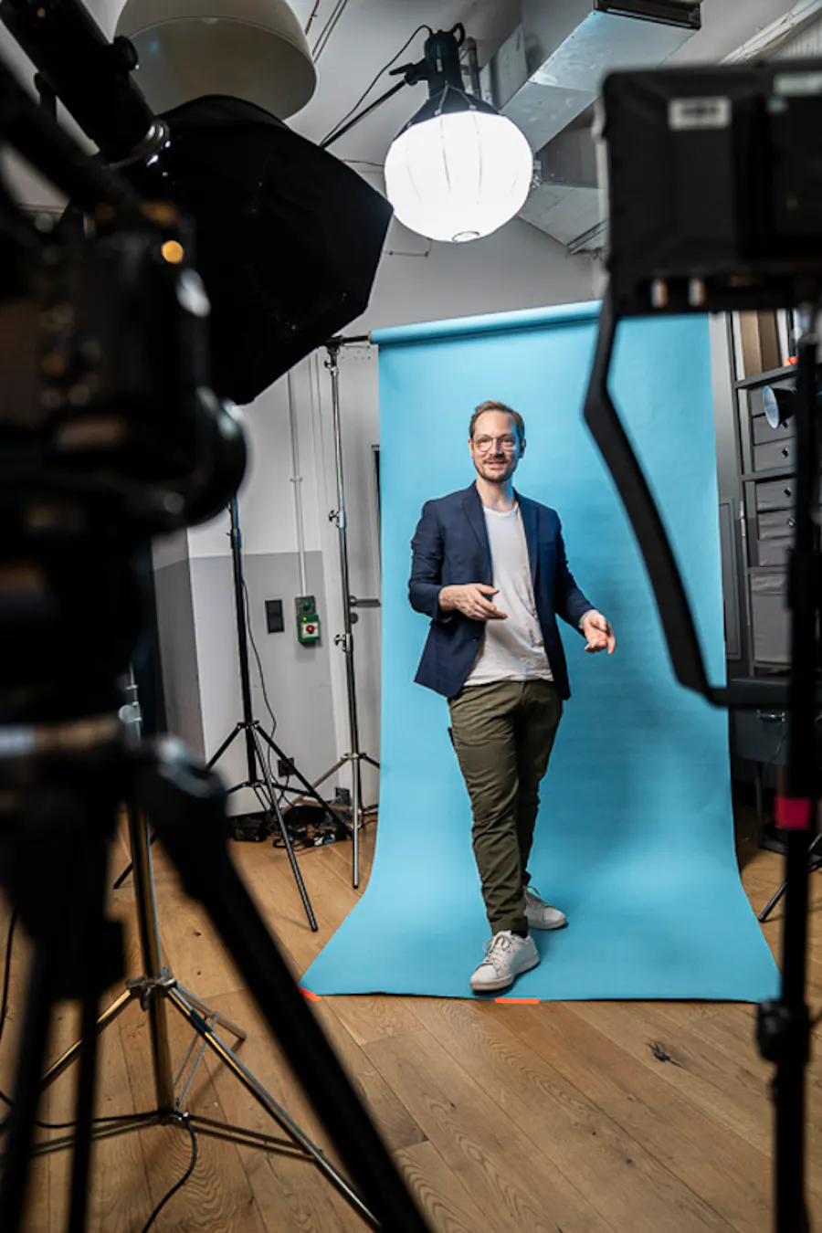Moderator vor blauem Hintergrund im Studio.