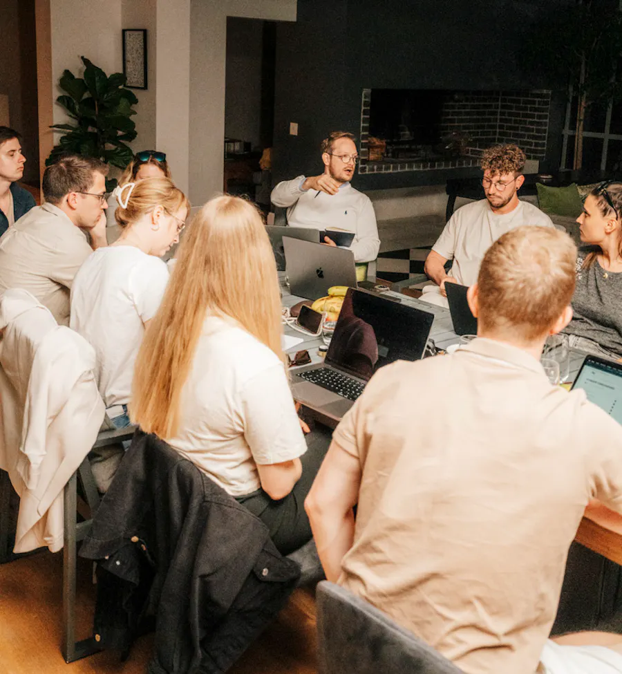 Team-Workshop am großen Tisch mit Laptops.