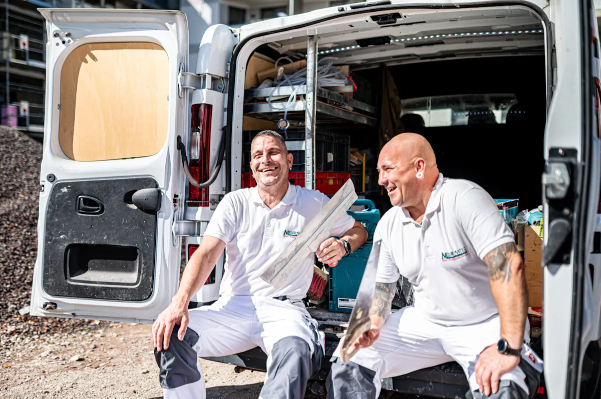 Zwei Kollegen lachen in der Pause am Transporter