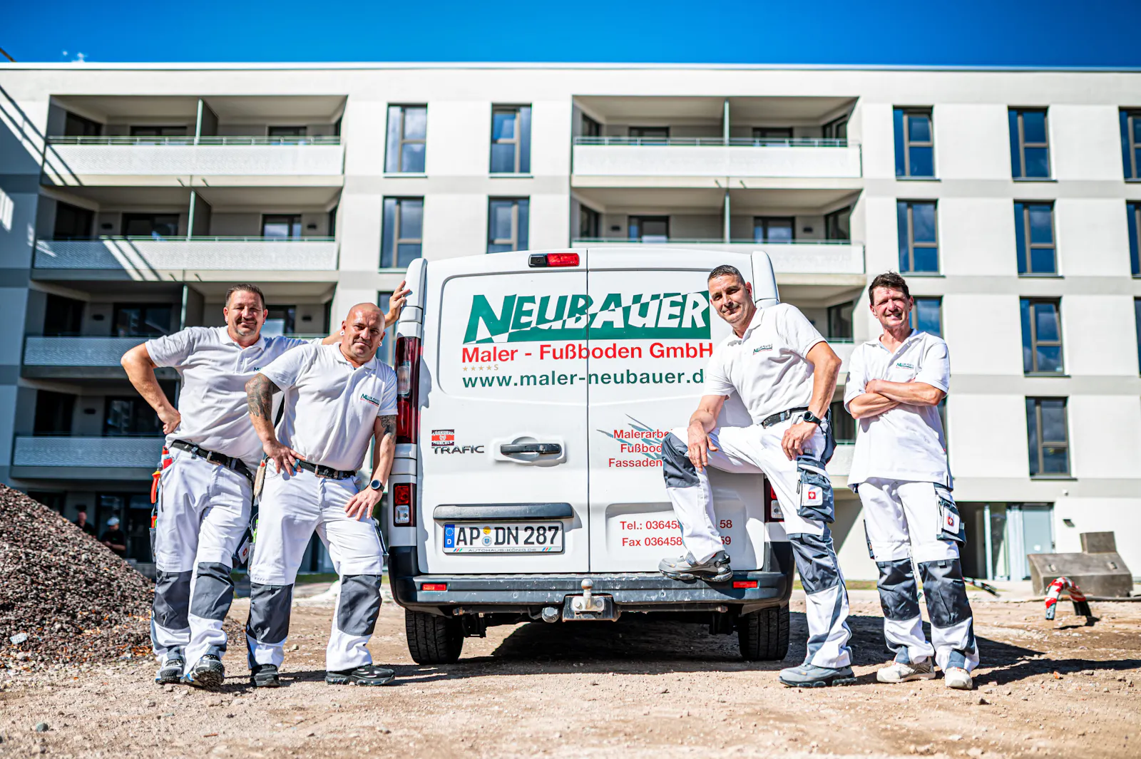 Team mit Firmenwagen vor Neubau